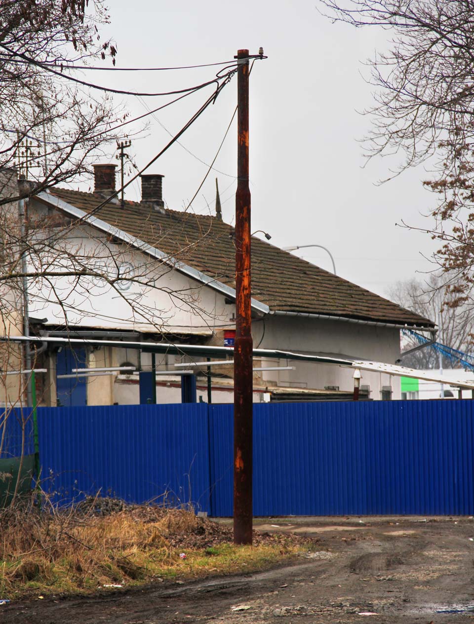 Rezivějící sloup trakčního vedení je poslední připomínkou elektrifikace - patrně již ale jen trolejbusové vozovny, která v areálu stanice dočasně působila. Rezivějící sloup trakčního vedení je poslední připomínkou elektrifikace - patrně již ale jen trolejbusové vozovny, která v areálu stanice dočasně působila.