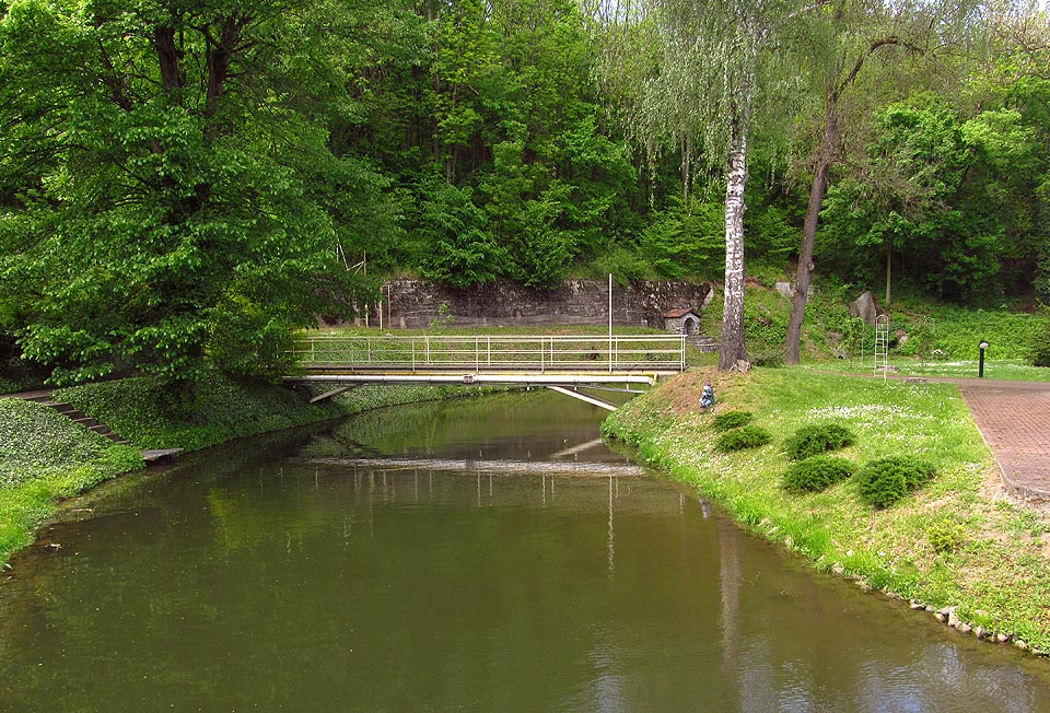 Nejzápadnější zátoka Cacovického náhona se zařezává do úbočí Holých hor, kde stojí pod opěrnou zdí také záhadná kamenná studánka. Nepřístupná zahrada zněmožňuje bližší průzkum. Nejzápadnější zátoka Cacovického náhona se zařezává do úbočí Holých hor, kde stojí pod opěrnou zdí také záhadná kamenná studánka. Nepřístupná zahrada zněmožňuje bližší průzkum.