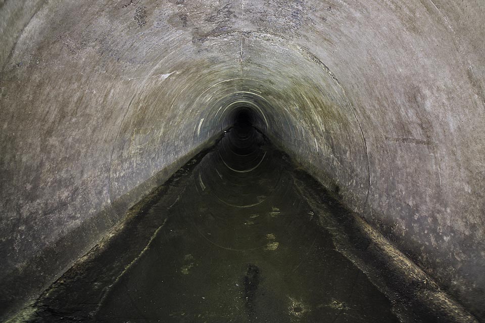 Šachty na povrch ustávají, místo betonových rour kráčíme nyní monolitickým tunelem. nad námi jsou desítky metrů zeminy, marně si lámeme hlavu, kam vlastně štola do hlubin země míří. Až později zjišťujeme, že jsme se stočili pod Stránskou skálu.