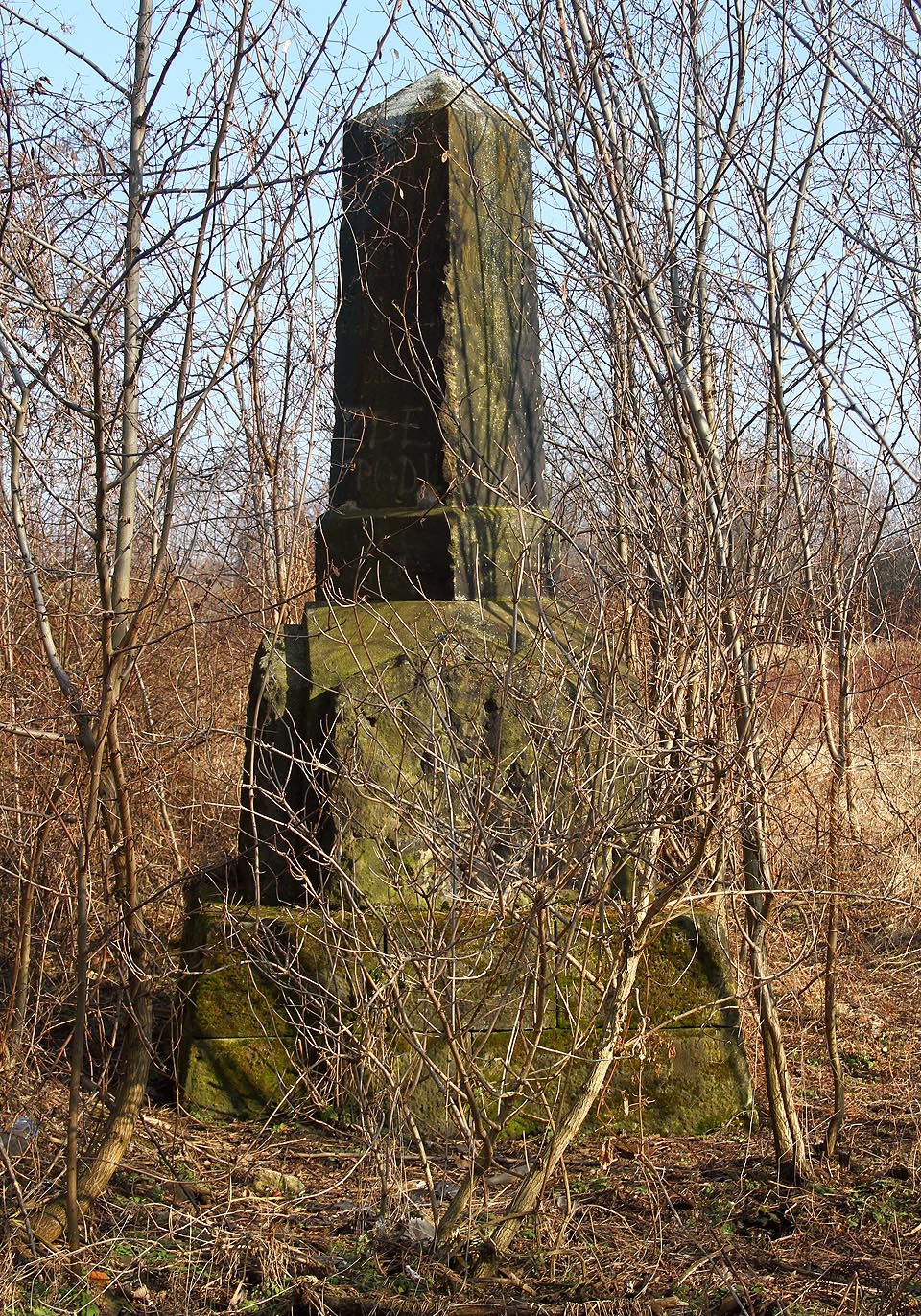 Čtevrhranný obelisk je zasazen v masivní základně z kyklopských kamenů. Čtevrhranný obelisk je zasazen v masivní základně z kyklopských kamenů.