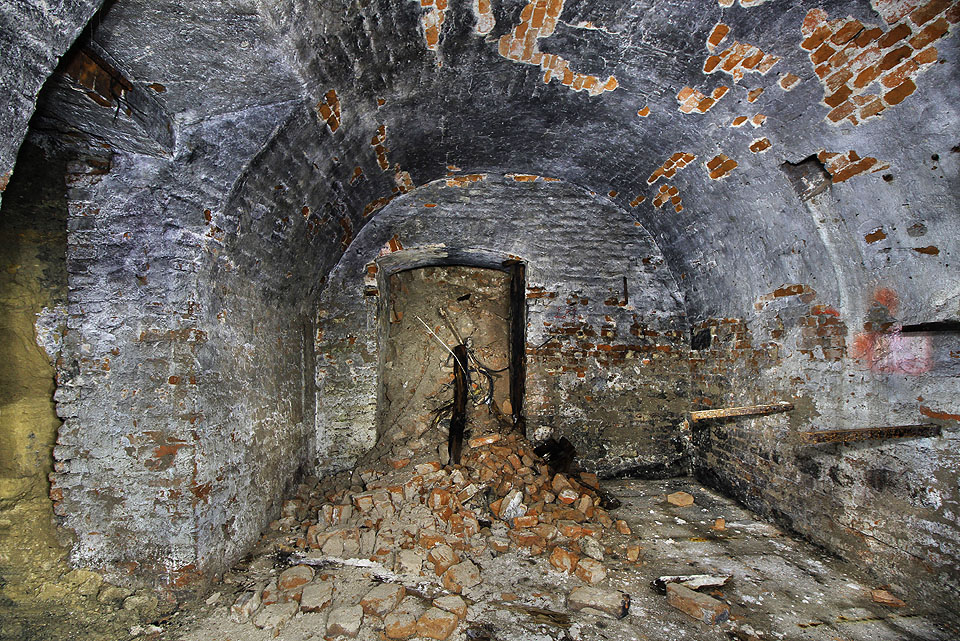 Také na východní straně pokračuje podzemí do další místnosti - jediné nevydřevené, za to se dvojicí dveří vedoucích doslova do nitra země. Dovnitř se valí hlína a suť, kterou kdysi někdo podzemí zavalil. Také na východní straně pokračuje podzemí do další místnosti - jediné nevydřevené, za to se dvojicí dveří vedoucích doslova do nitra země. Dovnitř se valí hlína a suť, kterou kdysi někdo podzemí zavalil.
