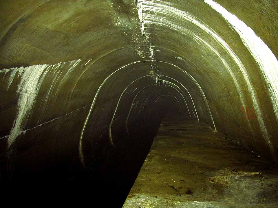 Výška nadloží rychle stoupá. Brzy se štola ocitá ve značné hloubce a sloupec vody tlačící na betonovou klenbu roste. Prasklinkami prochází voda pod velkým tlakem, rozprašuje se na jemnou mlhu nebo stéká po stěnách a vytváří sintrové krajky. Výška nadloží rychle stoupá. Brzy se štola ocitá ve značné hloubce a sloupec vody tlačící na betonovou klenbu roste. Prasklinkami prochází voda pod velkým tlakem, rozprašuje se na jemnou mlhu nebo stéká po stěnách a vytváří sintrové krajky.