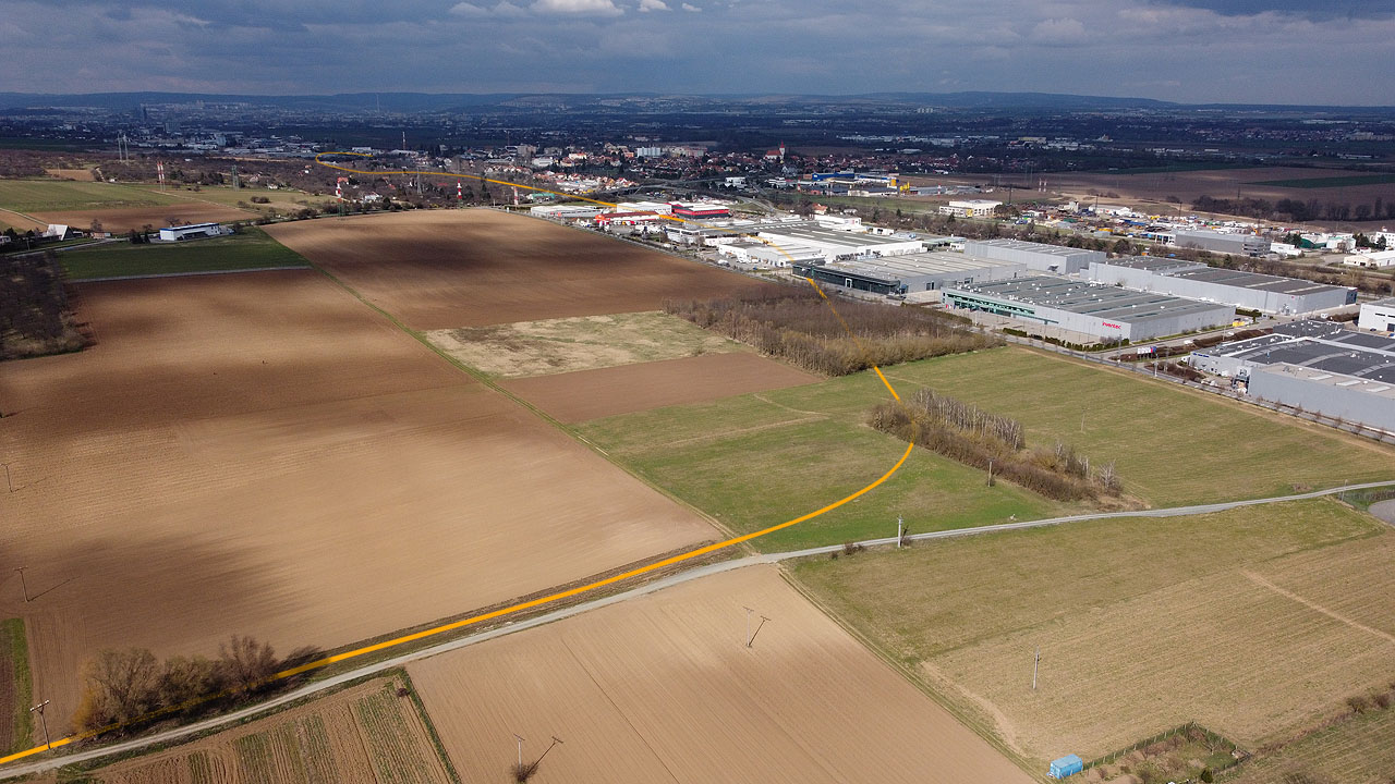 Detailní pohled na oblouk blíže Evropské ulice v Modřicích. Ani zde nezbylo po drážce takřka nic, těleso je rozorané a na místě lze nalézt jen nevýraznou terénní vlnu v travnaté ploše vpravo od středu snímku. Detailní pohled na oblouk blíže Evropské ulice v Modřicích. Ani zde nezbylo po drážce takřka nic, těleso je rozorané a na místě lze nalézt jen nevýraznou terénní vlnu v travnaté ploše vpravo od středu snímku.