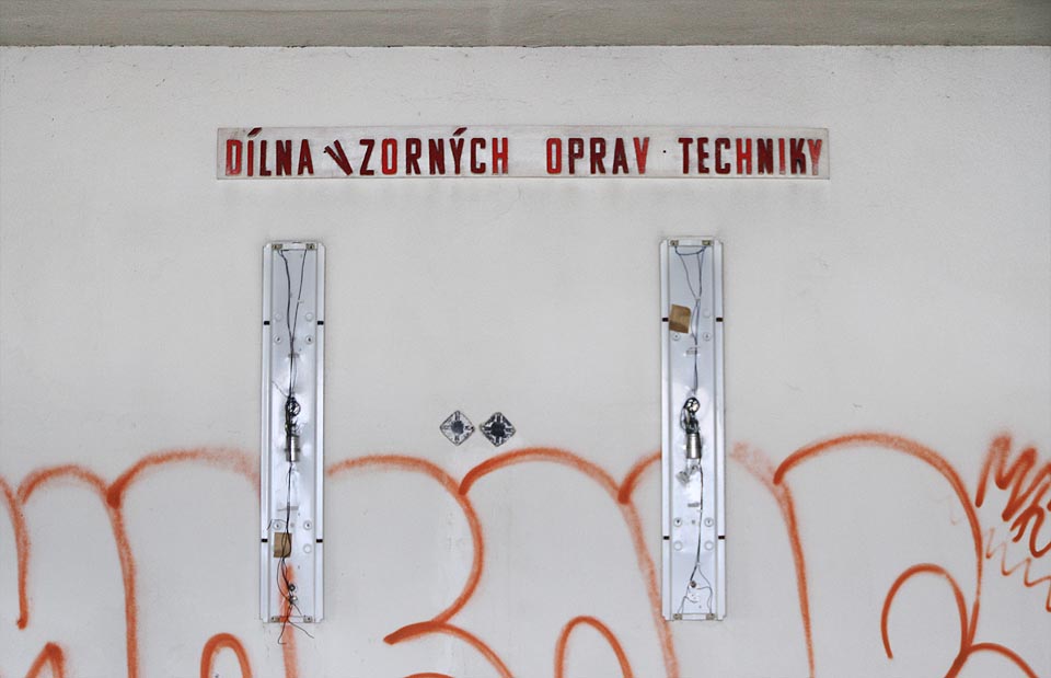 Stěnu zde zdobí nápis „dílna vzorných oprav techniky“. Stěnu zde zdobí nápis „dílna vzorných oprav techniky“.